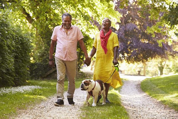 Couple holding hands and walking dog