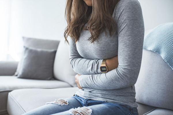 Woman sitting, holding her stomach