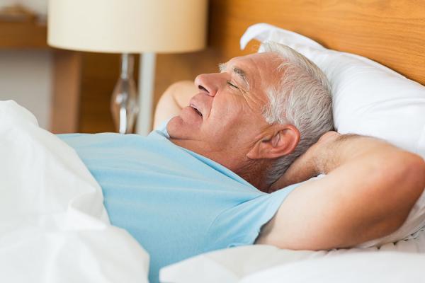 Man sleeping on his back in bed