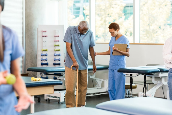 Nurse helping man with cane