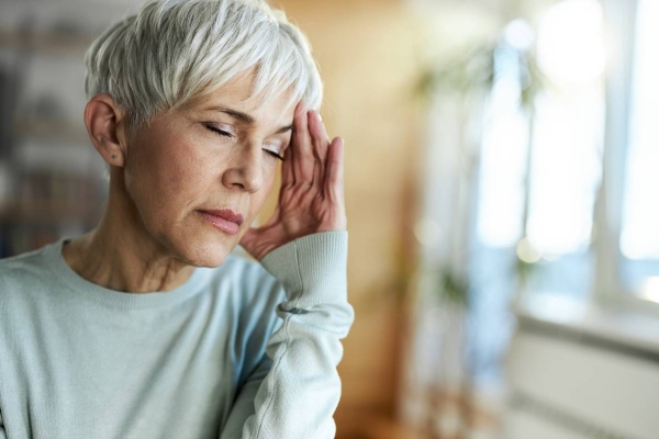 A woman experiencing a headache holds her head while seeking relief from the pain.